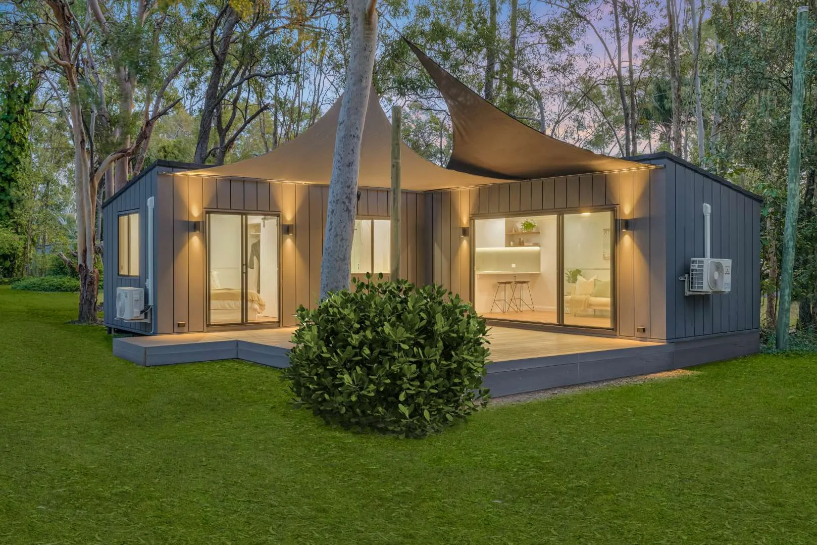 Tiny Home Central modular home lit at dusk on a landscaped block